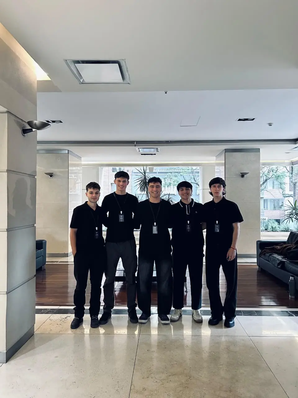 Cinco integrantes del equipo de Tecnomotion, vestidos de negro y con credenciales, en el hall de un edificio