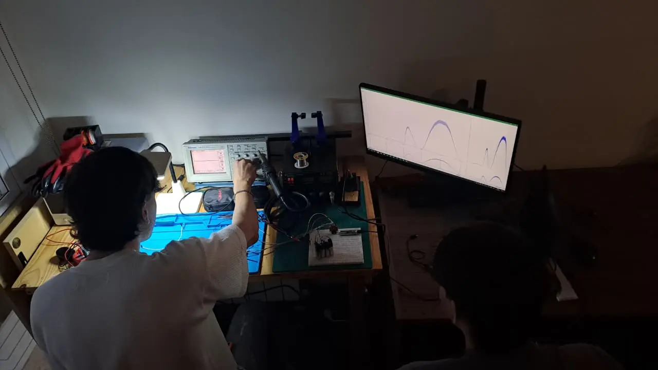 Integrante del equipo midiendo una señal en el osciloscopio, junto a un monitor con curvas registradas